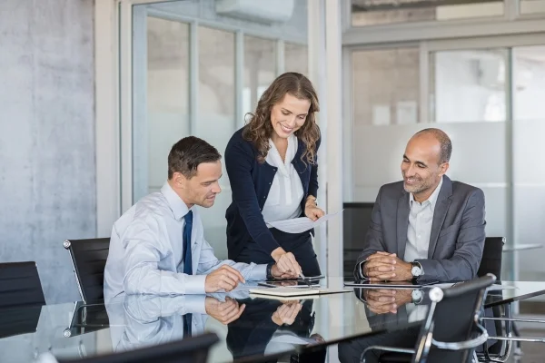 Drei Geschäftsleute besprechen Dokumente am Konferenztisch im Büro und entwickeln gemeinsam Strategien mit umfassendem 360°-Blick auf Unternehmensentscheidungen.