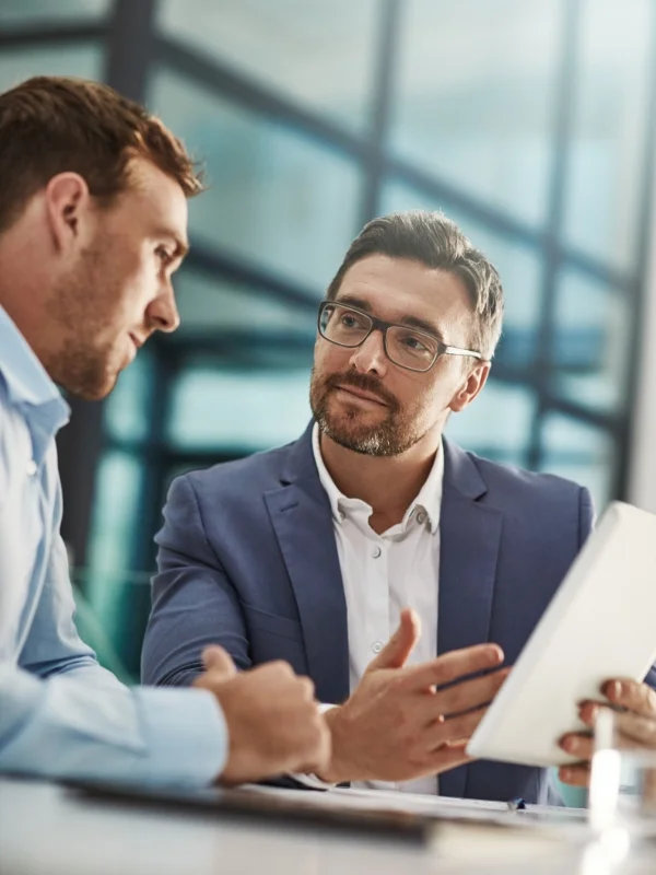 Berater erläutert einem Kunden auf einem Tablet individuelle Strategien während eines persönlichen Beratungsgesprächs zu maßgeschneiderten Einzellösungen im Büro.