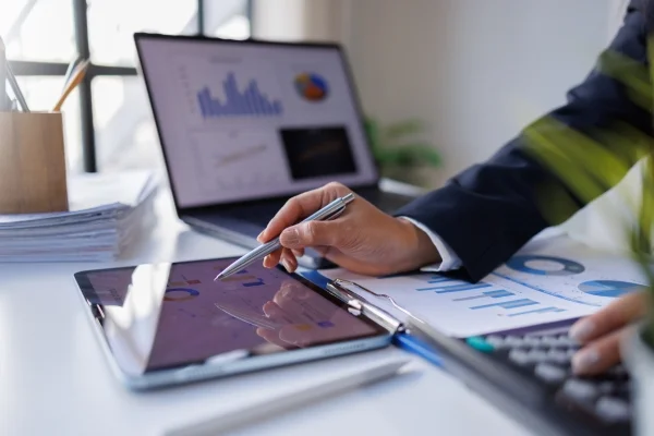 Berater wertet digitale Diagramme auf Tablet und Laptop aus, um datenbasierte Analysen und individuelle Einzellösungen für Unternehmen zu entwickeln.