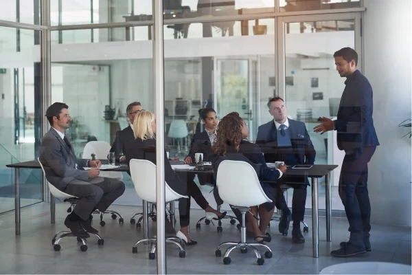 Manager präsentiert Strategien vor Team im modernen Konferenzraum, gemeinsame Analyse und Diskussion zur Entwicklung passgenauer Individuallösungen.