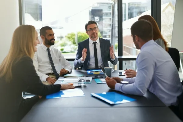 Geschäftsteam diskutiert Strategien und Unterlagen am Konferenztisch im Büro und entwickelt gemeinsam durchdachte Individuallösungen für Unternehmensentscheidungen.