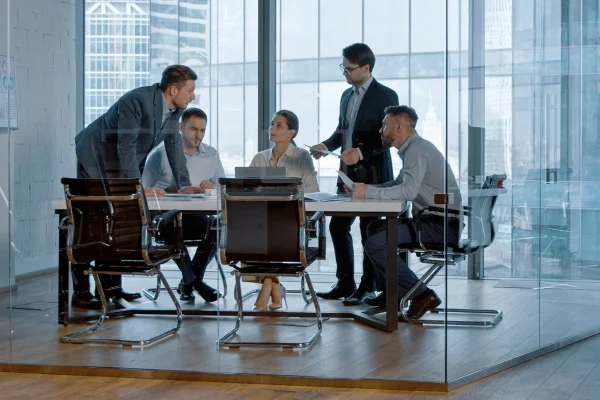 Team bespricht Strategien und Dokumente im modernen Konferenzraum und entwickelt gemeinsam kreative Individuallösungen für komplexe geschäftliche Herausforderungen.