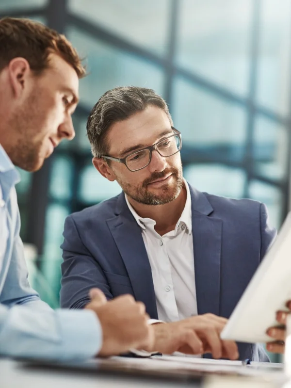 Zwei Berater analysieren gemeinsam Daten auf einem Tablet und besprechen strategische Maßnahmen zur Kanzleientwicklung im Rahmen von ProKanzlei.