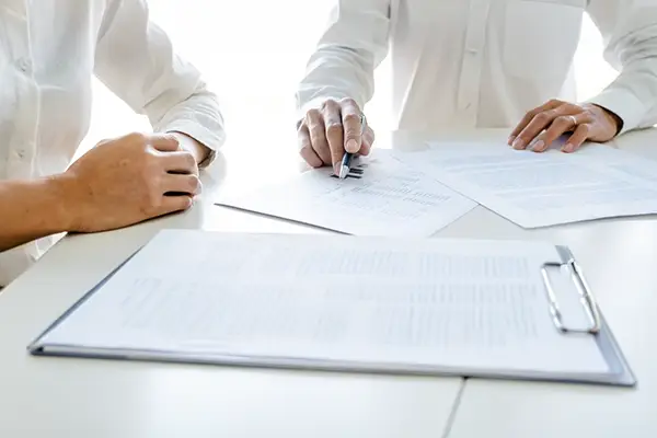 Berater und Mandant besprechen Finanzunterlagen am Tisch und analysieren Kennzahlen gemeinsam im Rahmen der Kanzleientwicklung mit ProKanzlei.