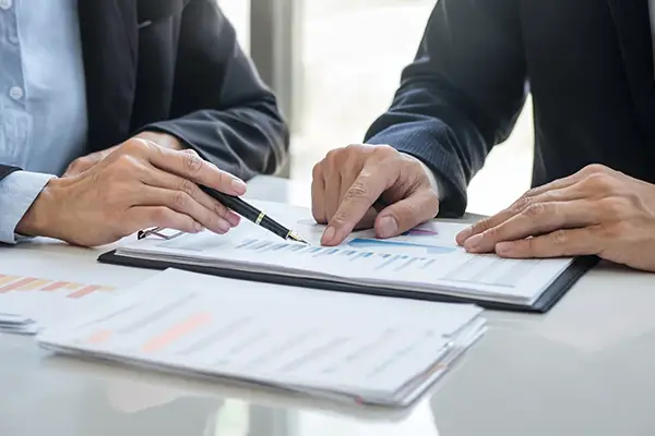 Zwei Berater analysieren gemeinsam Kennzahlen und Diagramme auf Unterlagen am Tisch im Rahmen einer strategischen Kanzleientwicklung mit ProKanzlei.